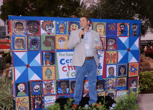 Man with microphone standing in front of mural