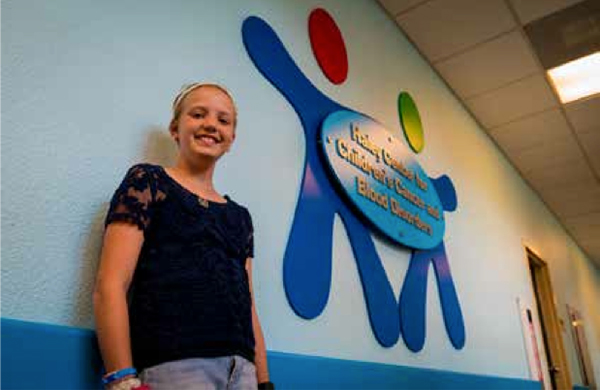 Heather Moore, 12, diagnosed with Leukemia and treated at Arnold Palmer Hospital, stands in the hallway with the new Haley Center for Children’s Cancer and Blood Disorders sign on the second floor of the hospital.