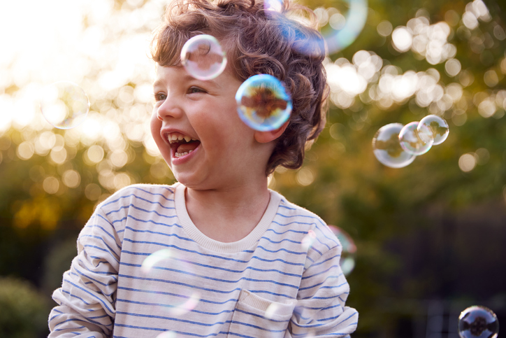Young boy smiling as iridescent bubbles surround him