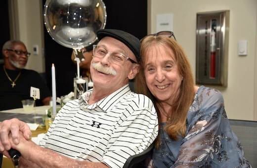 man in wheelchair and woman smiling with balloon behind them