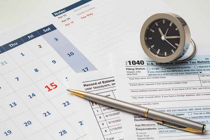 Tax return 1040, one-month calendar and alarm clock on white background, USA tax due date marked on calendar, taxation concept